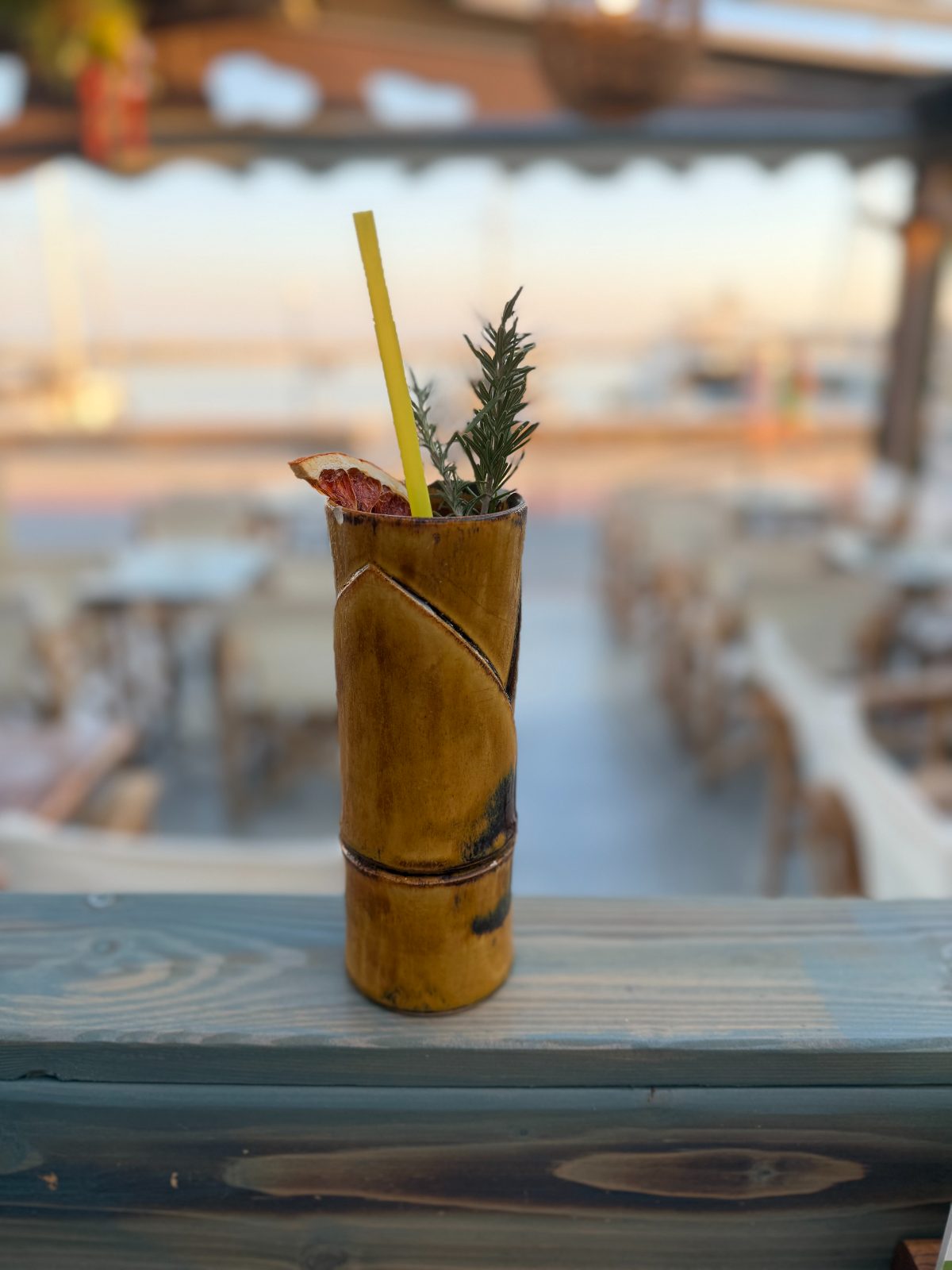 Bamboo mug cocktail garnished with citrus and rosemary, marina at dusk