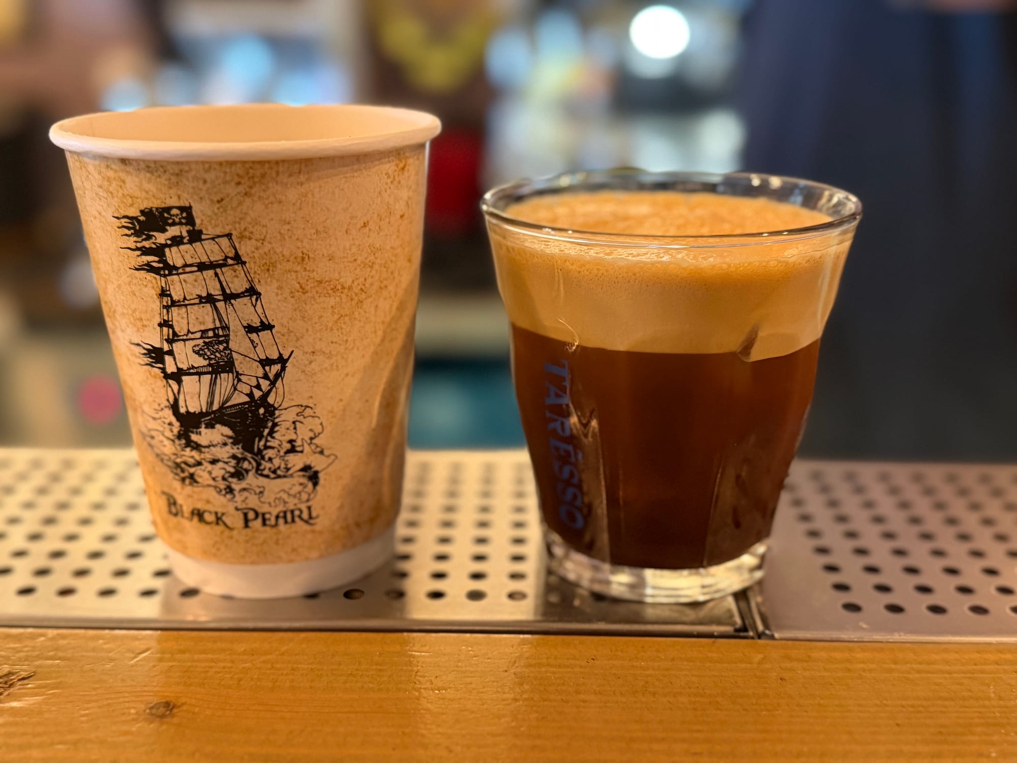 Black Pearl branded cup beside a glass of iced espresso