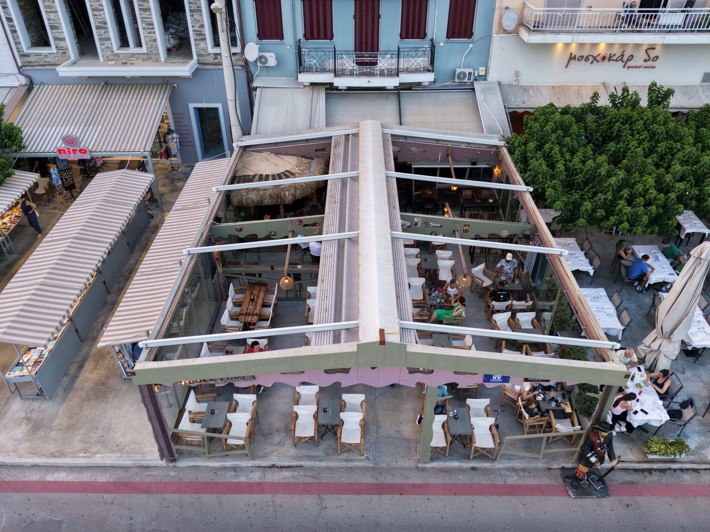 Aerial view of the Black Pearl terrace at golden hour with the BLACK PEARL sign lit above the guests